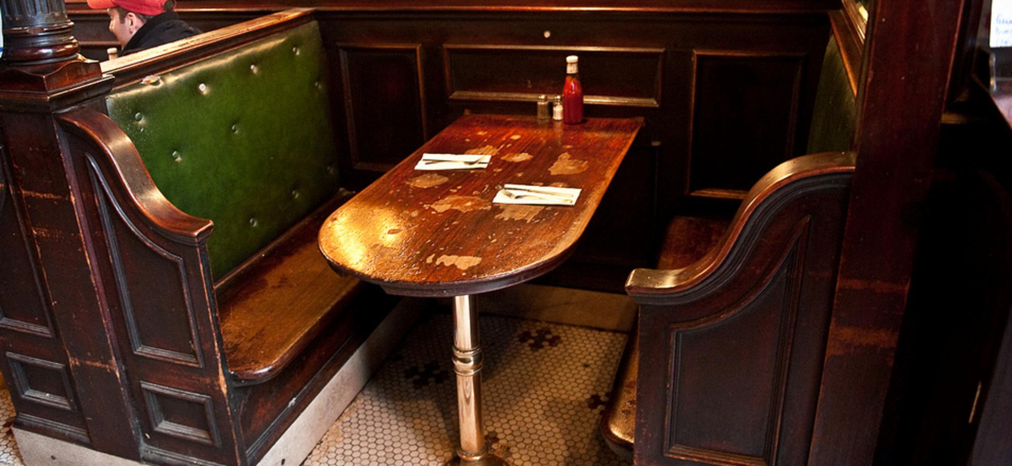 A table in a pub with benches each side, and cutlery laid out for two, but nobody there