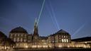 A pair of bright green lasers shining into (or maybe out from) the tower of Christiansborg, the Danish parliament building.