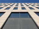 Looking almost directly up, the building fills the bottom 90% of the frame, a bit of clear blue sky above that. The grid of windows almost looks like floor tiles.