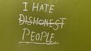 On a sickly-green colour toilet door, written in an almost glowing white, in pretty neat writing: 'I hate dishonest people', with the word 'dishonest' crossed out.